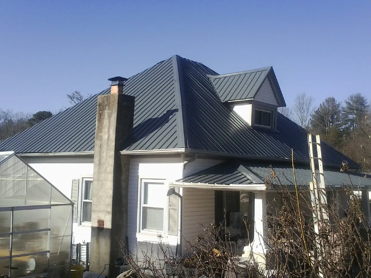 Dark blue standing seam metal roof on a white farmhouse with dormer — Slate & Tile Roof Repair by Roofing Brothers in Russells Point
