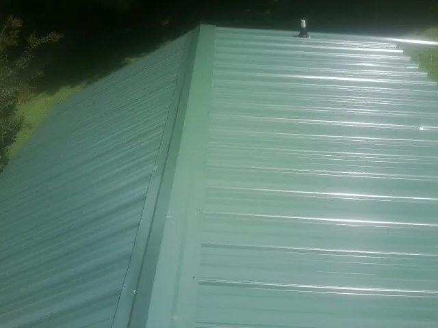 New green metal panels meeting at the ridge of a roof — Flat Roof Repair work by our crew in Russells Point