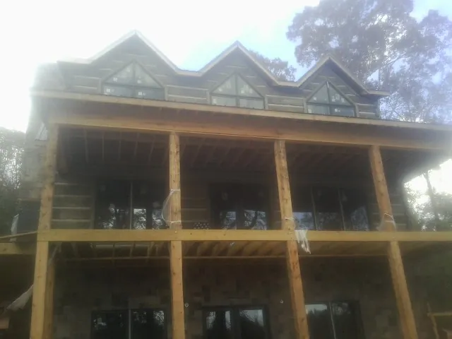 Dormers and porch framing on a large log home under construction — Roof Coating work by our crew in Russells Point