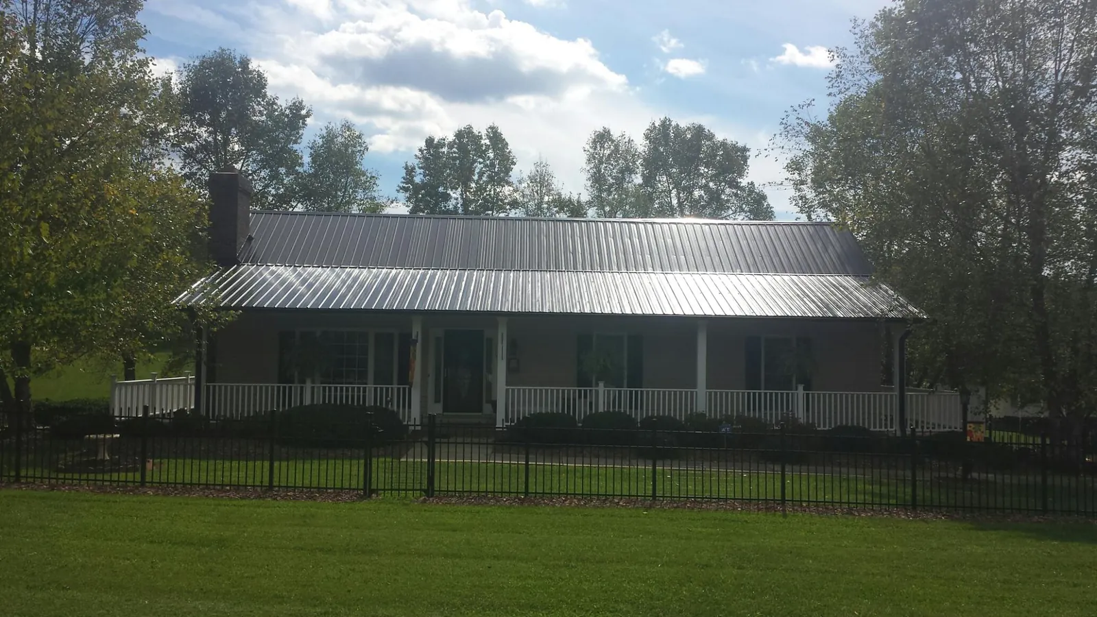 Gray metal roof on a brick ranch with a full width front porch — Gutter Guard Installation work by our crew in Russells Point