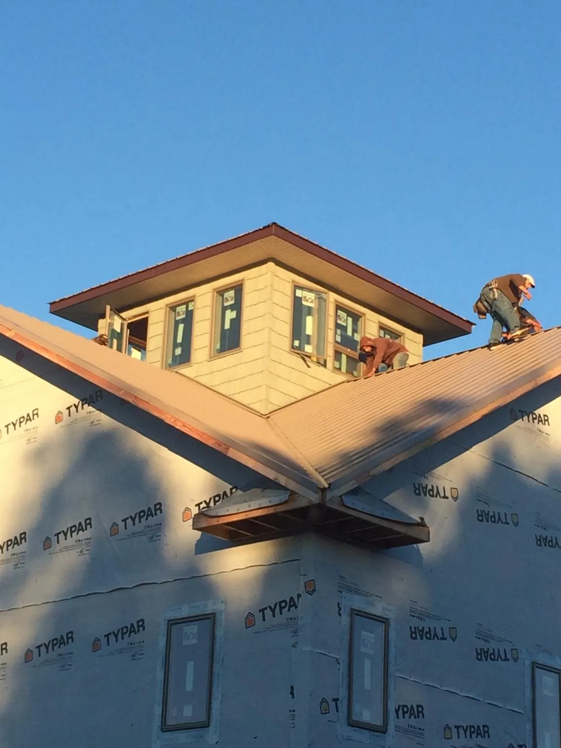 Roofers working around a rooftop cupola on a new metal roof at sunset — Roof Waterproofing in Russells Point by Roofing Brothers